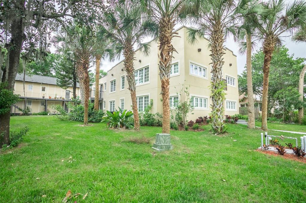 A multi-story apartment building with a beige exterior sits on a grassy lawn with palms — 915 E PALMETTO STREET, LAKELAND, FL