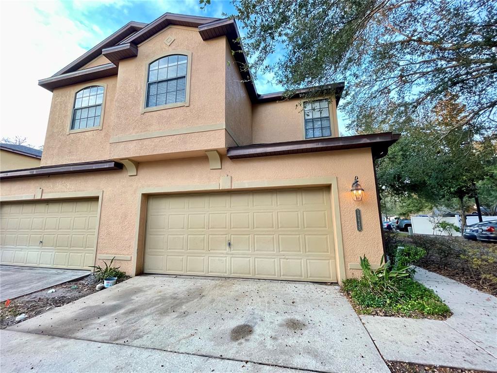 A two-story stucco townhouse features a two-car garage and a concrete driveway — 2944 OAK PARK WAY UNIT 1453, ORLANDO, FL