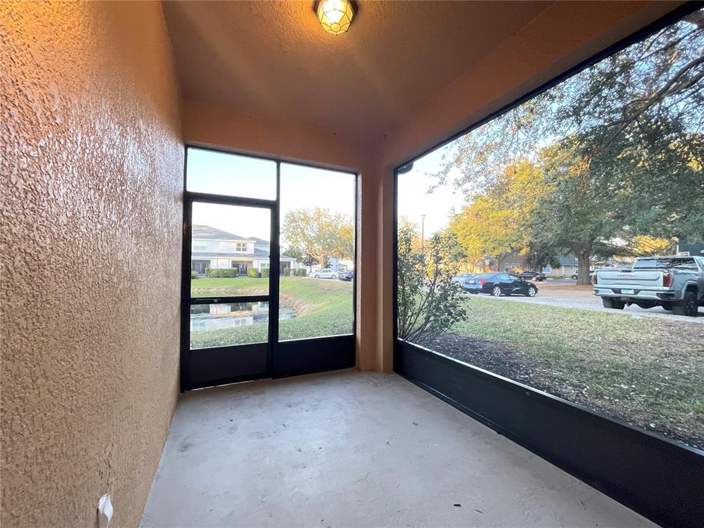 A screened-in porch with a concrete floor, a light fixture, and views of a pond — 2944 OAK PARK WAY UNIT 1453, ORLANDO, FL