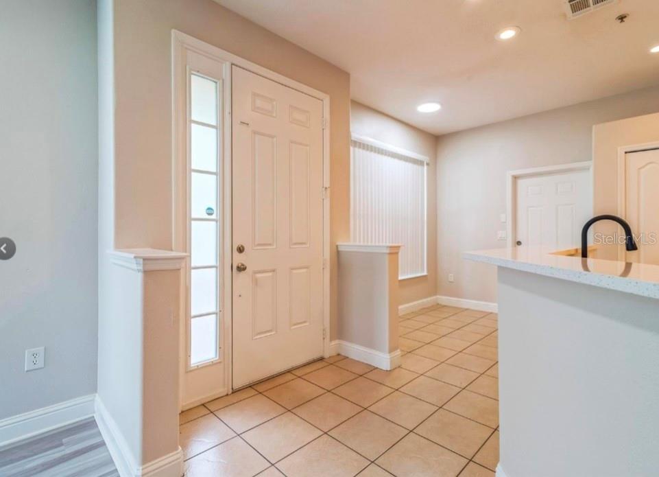 An entryway with tile flooring, a white front door, and a partial wall divider — 2944 OAK PARK WAY UNIT 1453, ORLANDO, FL