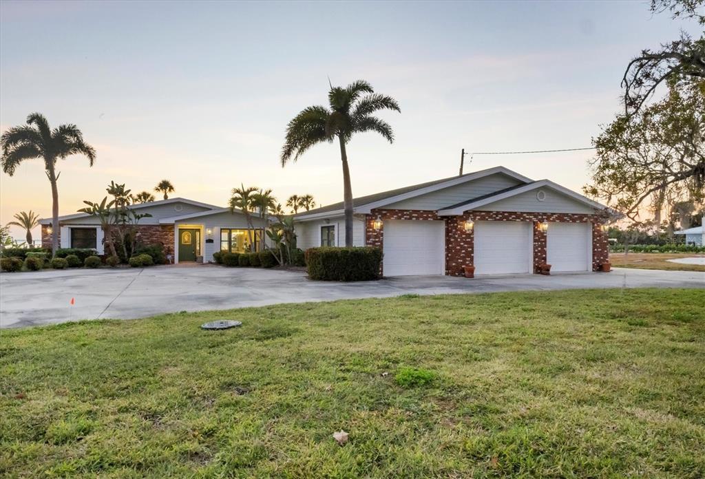 A single-story house with a three-car garage, brick accents, and palm trees in the yard — 7318 WESTMORELAND DRIVE, SARASOTA, FL