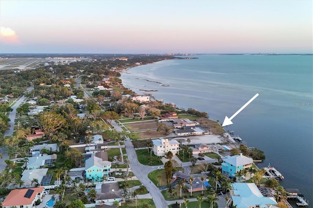 An aerial view shows a coastal neighborhood with houses along the water and a vacant lot — 7318 WESTMORELAND DRIVE, SARASOTA, FL