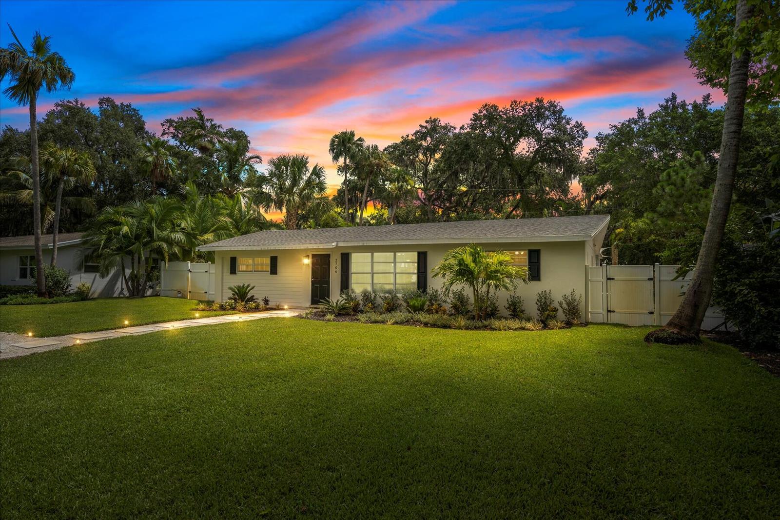 A single-story house with a white exterior, black shutters, and a lawn at sunset — 2706 10th Avenue, Vero Beach FL 32960, VERO BEACH, FL