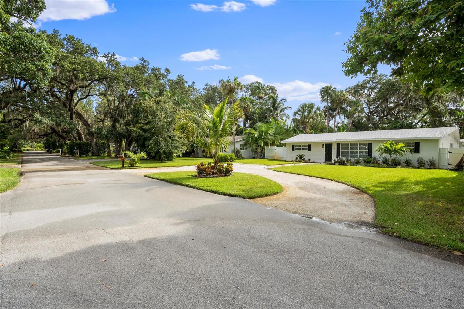 A white single-story house with a circular driveway sits on a grassy, tree-lined lot — 2706 10th Avenue, Vero Beach FL 32960, VERO BEACH, FL