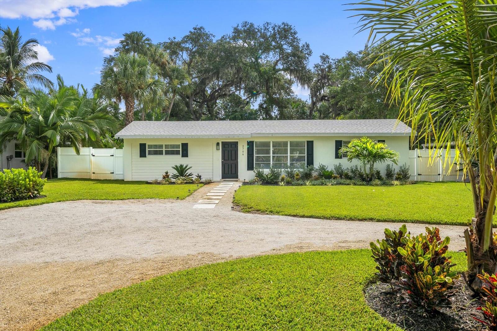 A single-story house with white siding, a gravel driveway, and a lush green lawn — 2706 10th Avenue, Vero Beach FL 32960, VERO BEACH, FL