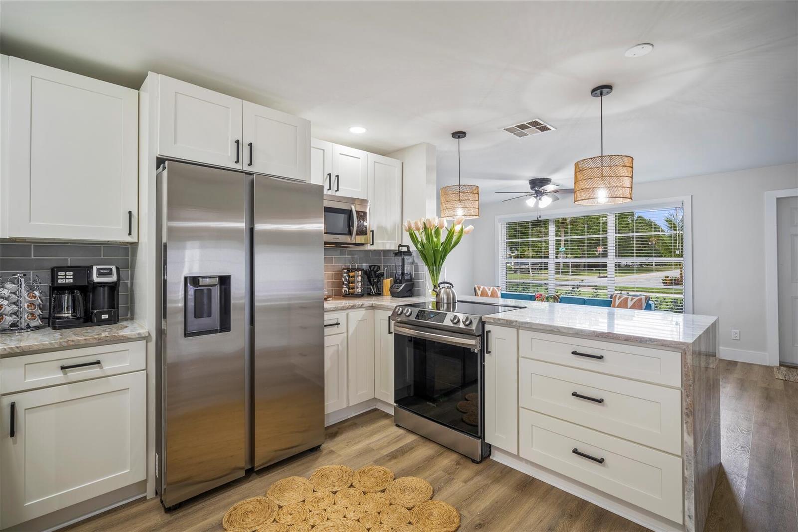 A modern kitchen features white cabinets, stainless steel appliances, and a marble-topped island — 2706 10th Avenue, Vero Beach FL 32960, VERO BEACH, FL