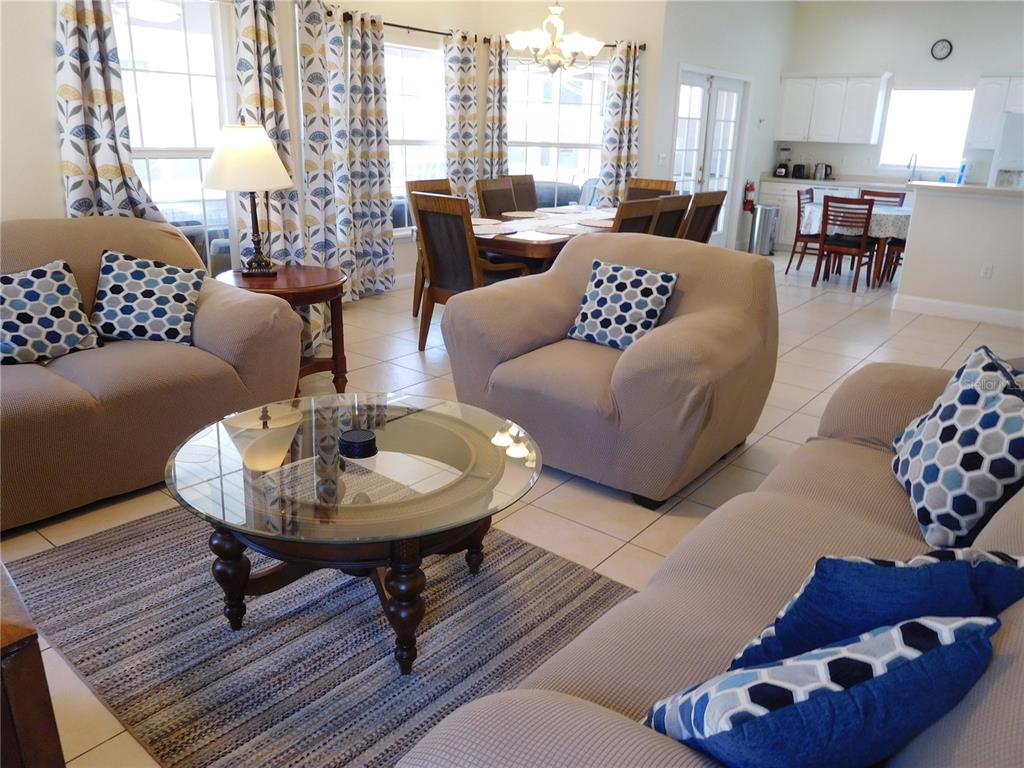 A living room with beige furniture, a glass coffee table, and an adjacent dining area — 422 VISTA DRIVE, DAVENPORT, FL