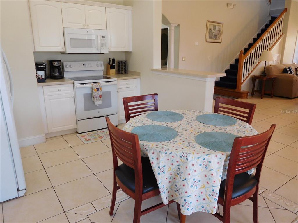A kitchen with white cabinets and appliances features a small dining table with four chairs — 422 VISTA DRIVE, DAVENPORT, FL