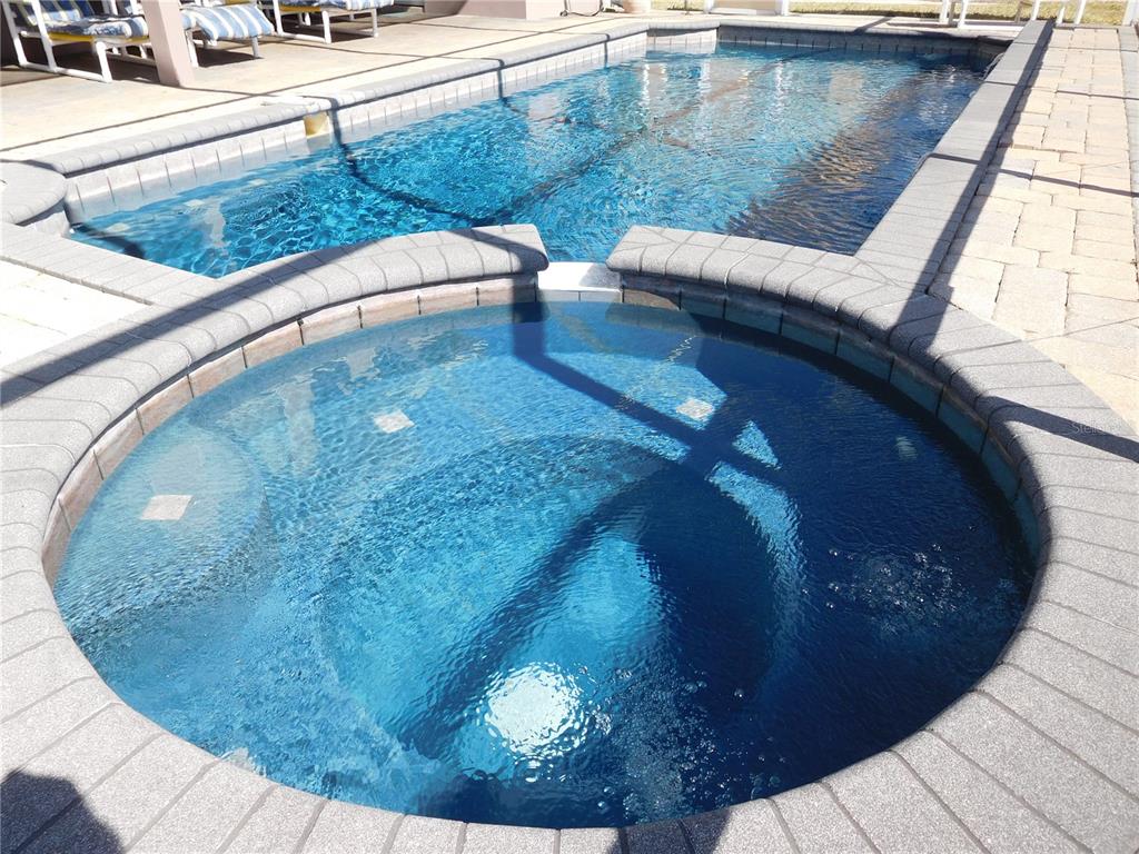 A circular spa sits adjacent to a rectangular swimming pool on a paved patio — 422 VISTA DRIVE, DAVENPORT, FL