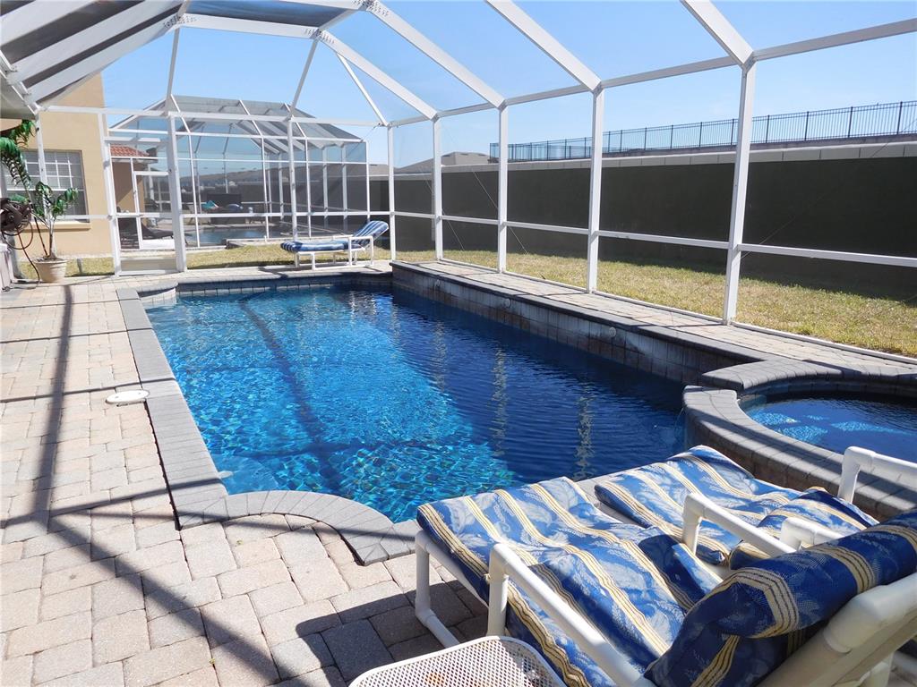 A screened-in swimming pool and hot tub sit on a paved patio in a backyard — 422 VISTA DRIVE, DAVENPORT, FL