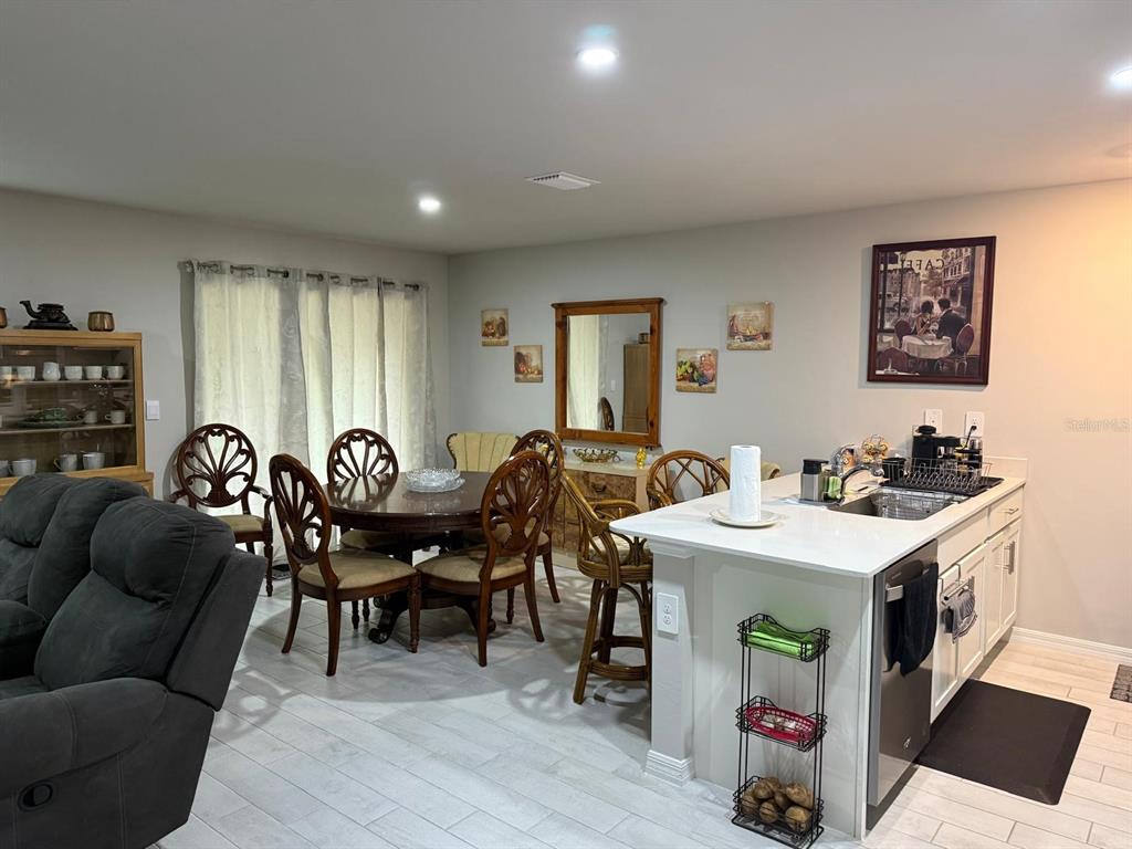 A dining area with a wooden table and chairs sits adjacent to a kitchen island — 1580 BISCAYNE DRIVE, PORT CHARLOTTE, FL