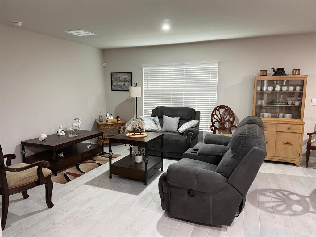A living room features gray reclining furniture, a wooden coffee table, and a light wood hutch — 1580 BISCAYNE DRIVE, PORT CHARLOTTE, FL
