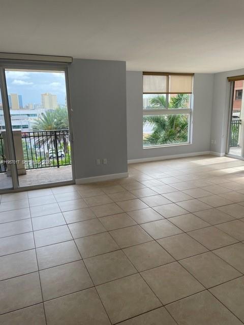 An empty room with beige tile flooring, large windows, and a balcony overlooking city buildings — 2650 SW 37th Ave # 501, Miami FL 33133, MIAMI, FL
