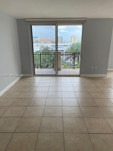 An empty room with light-colored tile flooring features a sliding glass door leading to a balcony — 2650 SW 37th Ave # 501, Miami FL 33133, MIAMI, FL