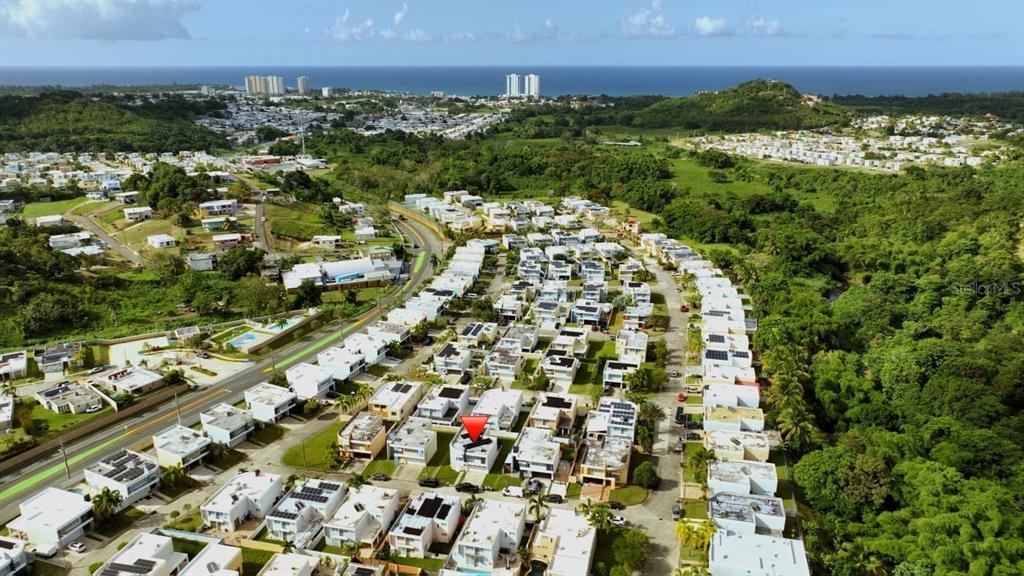 An aerial view shows a residential neighborhood with white houses and a red location marker — Calle Isleña HACIENDA PALOMA, LUQUILLO, PR