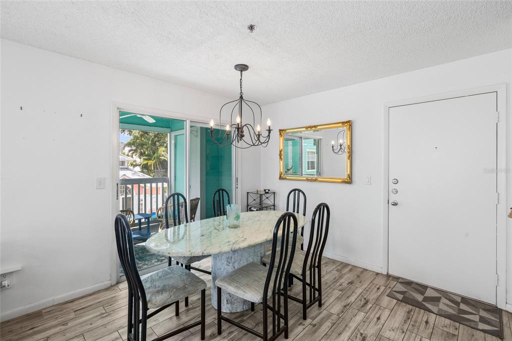 A dining room features a marble table, black chairs, a chandelier, and a sliding glass door — 3002 W CLEVELAND STREET UNIT B6, TAMPA, FL