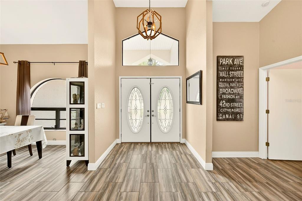 An entryway features double front doors, a geometric chandelier, and wood-look tile flooring — 9757 HERMOSILLO DRIVE, NEW PORT RICHEY, FL