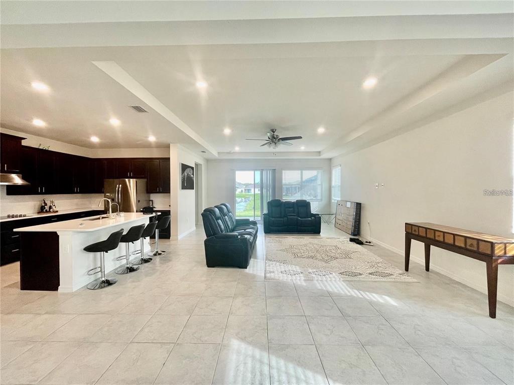 An open-concept kitchen and living area features dark cabinetry, a white island, and tile flooring — 14311 59TH CIRCLE E, BRADENTON, FL