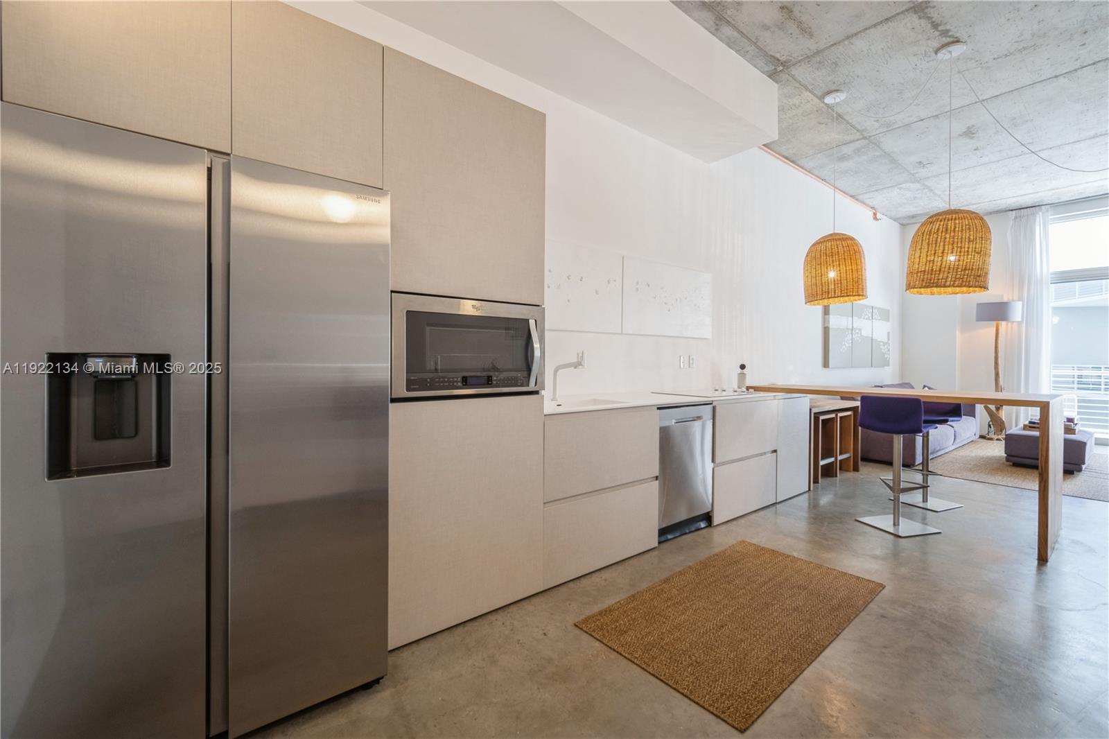 A modern kitchen features stainless steel appliances, light cabinetry, and a concrete ceiling — 2001 Meridian Ave # 512, Miami Beach FL 33139, MIAMI BEACH, FL