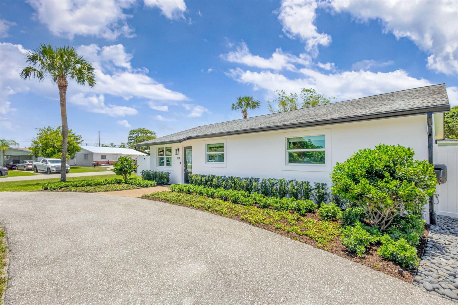 A white single-story house with a paved driveway and landscaped yard under a blue sky — 204 W Whitney Drive, Jupiter FL 33458, JUPITER, FL