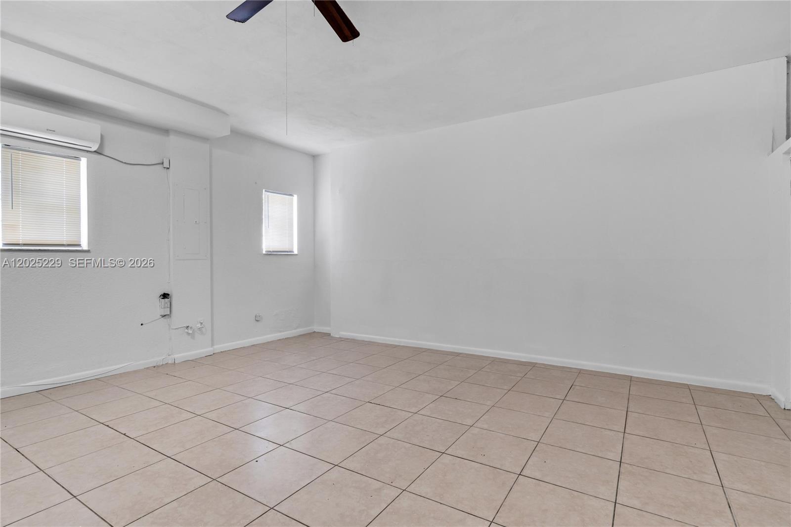 An empty room features white walls, beige tile flooring, two windows, and a ceiling fan — 15251 NW 89th Ave #A # A, Miami Lakes FL 33018, MIAMI LAKES, FL