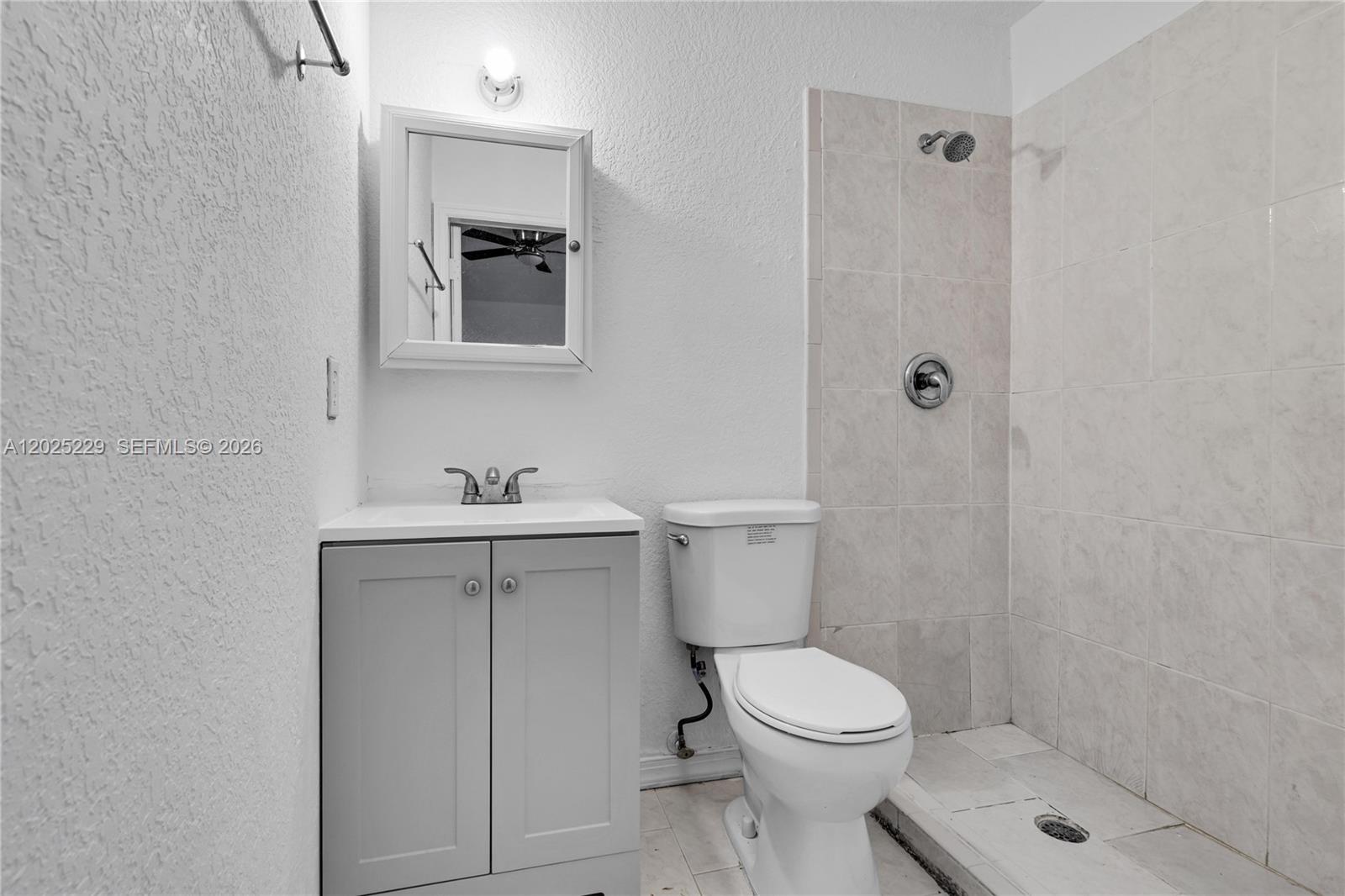 A bathroom features a gray vanity, a white toilet, and a tiled walk-in shower — 15251 NW 89th Ave #A # A, Miami Lakes FL 33018, MIAMI LAKES, FL