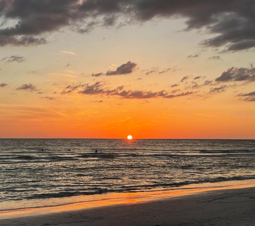 A sunset view over the ocean with silhouettes of people swimming in the water — 33894 OIL WELL ROAD, PUNTA GORDA, FL