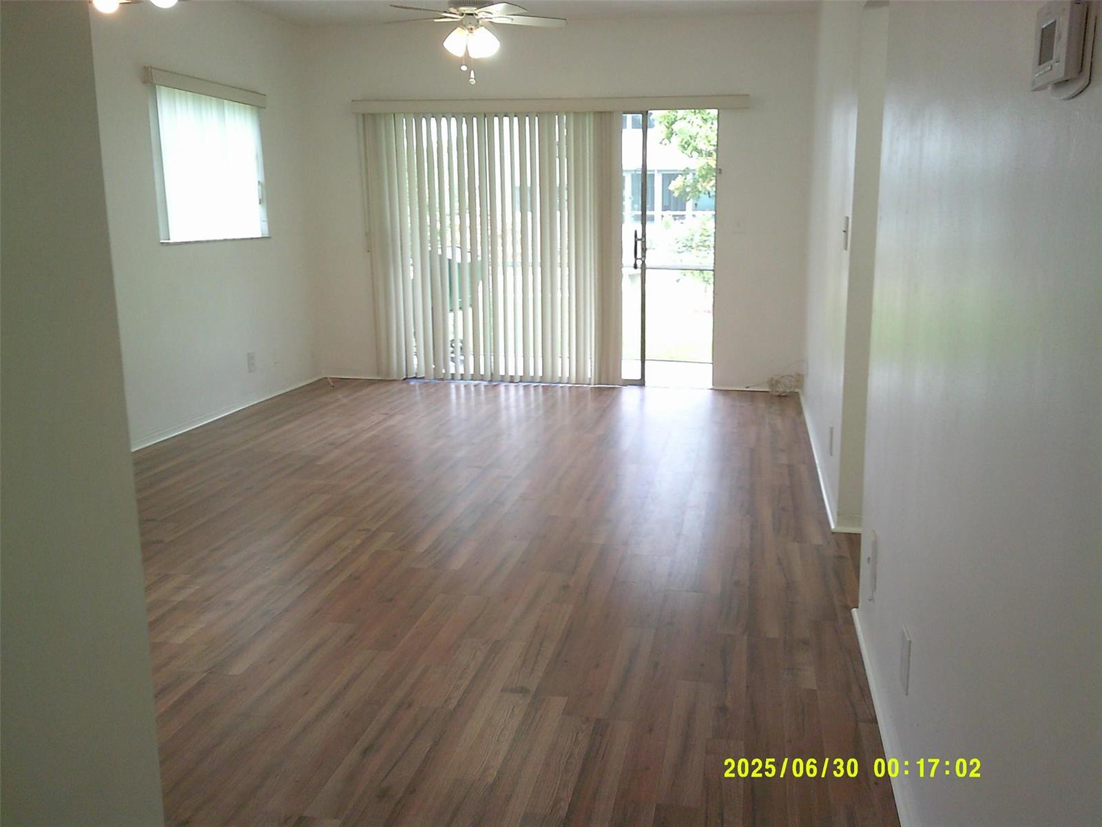 An empty living room features wood-look flooring, a ceiling fan, and a sliding glass door — 5800 Margate Boulevard # 4, Margate FL 33063, MARGATE, FL