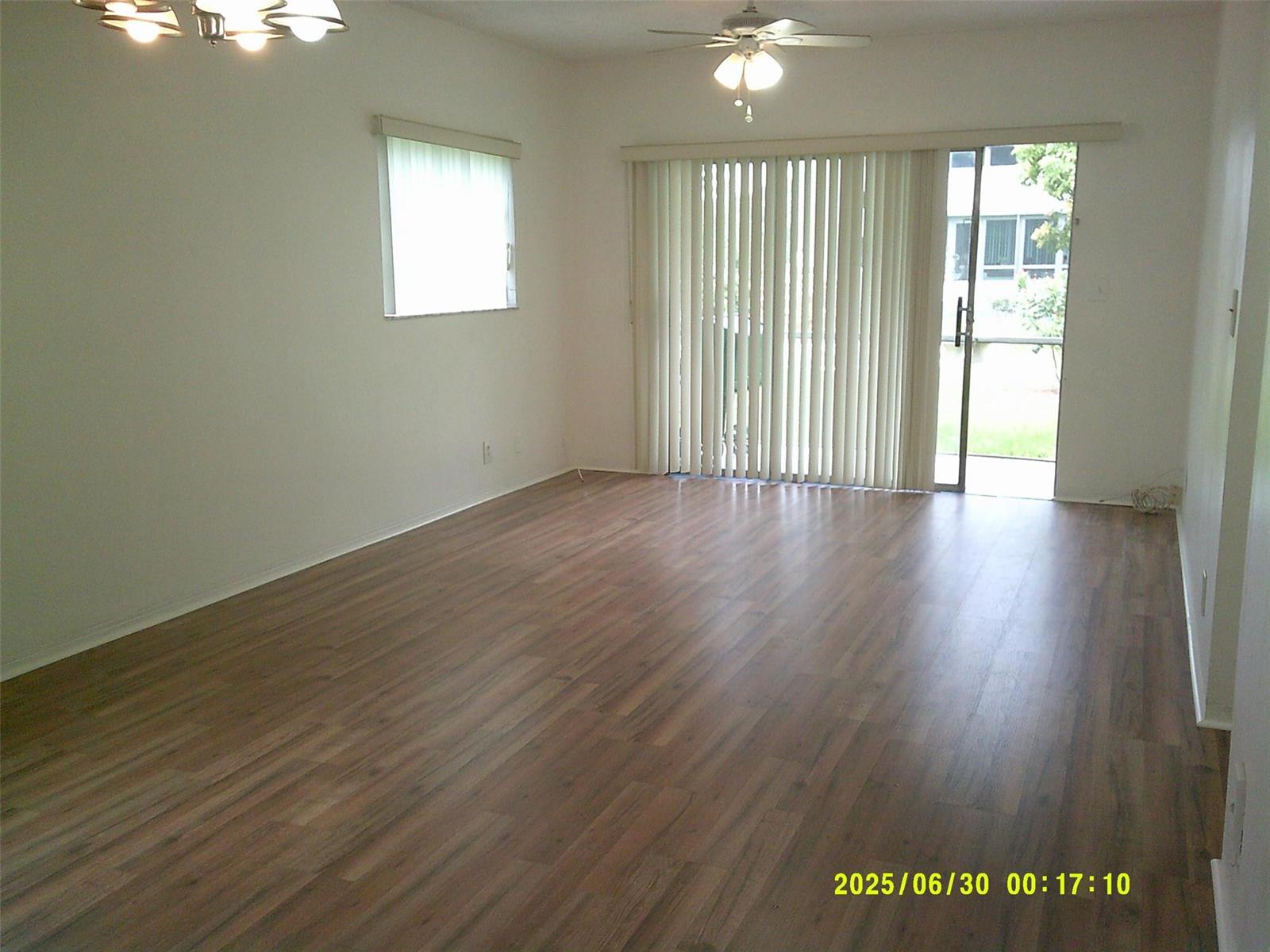 An empty living room features wood-look flooring, a ceiling fan, and sliding glass patio doors — 5800 Margate Boulevard # 4, Margate FL 33063, MARGATE, FL