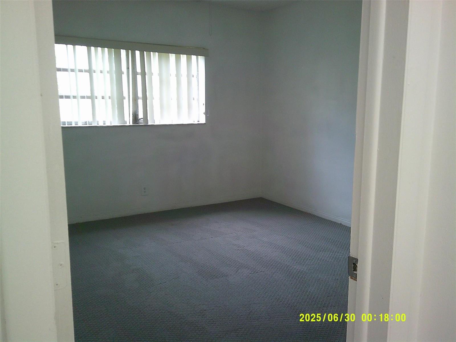 An empty bedroom with gray carpet, white walls, and vertical blinds on the window — 5800 Margate Boulevard # 4, Margate FL 33063, MARGATE, FL
