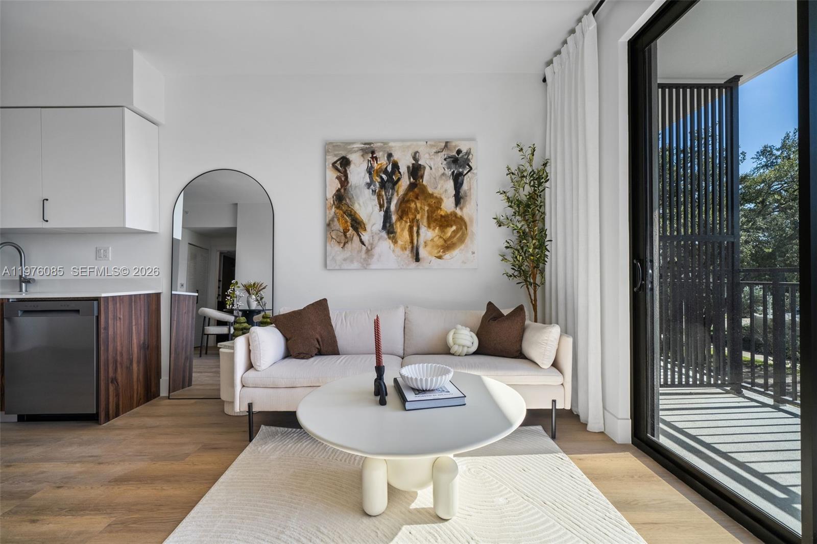A modern living room features a cream sofa, round coffee table, and abstract wall art — 2479 NE 192nd St # 209, Miami FL 33180, MIAMI, FL