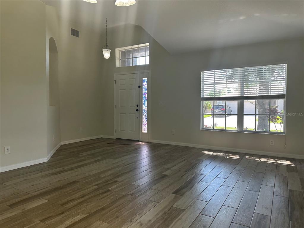 An entryway with wood-look tile flooring, a vaulted ceiling, and a front door with sidelights — 3145 DUNSTABLE DRIVE, LAND O LAKES, FL