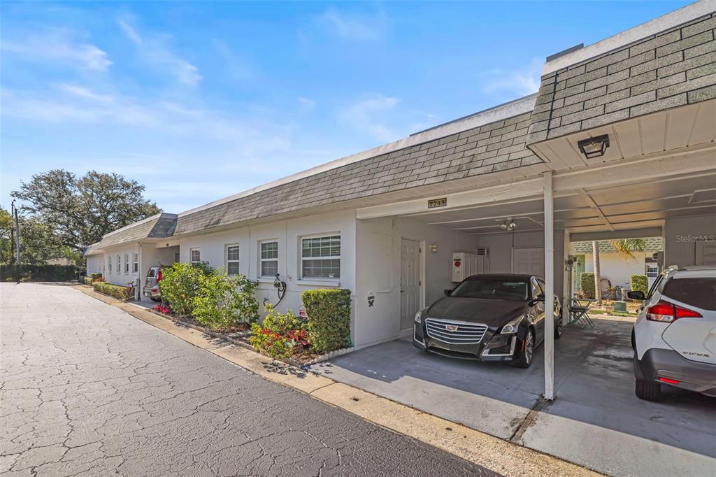 A single-story residential building features a covered carport with two parked cars — 7743 39TH TERRACE N, ST PETERSBURG, FL