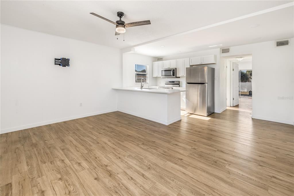 An open-concept kitchen and living area featuring light wood flooring and stainless steel appliances — 212 S DAYTONA AVENUE UNIT 1, FLAGLER BEACH, FL