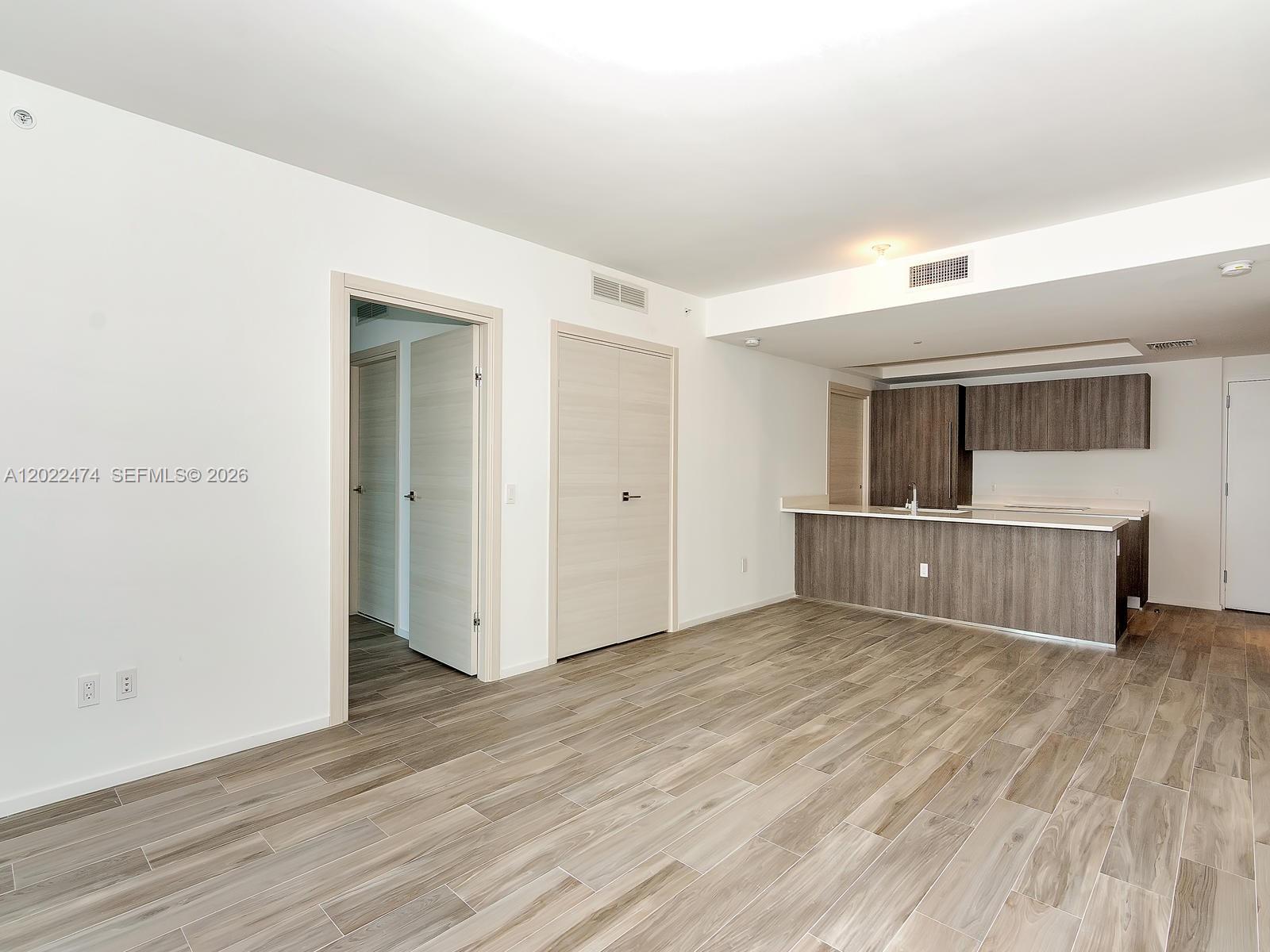 An open-concept living area features light wood-look tile flooring and a kitchen with dark cabinetry — 801 S Miami Ave # 2310, Miami FL 33131, MIAMI, FL