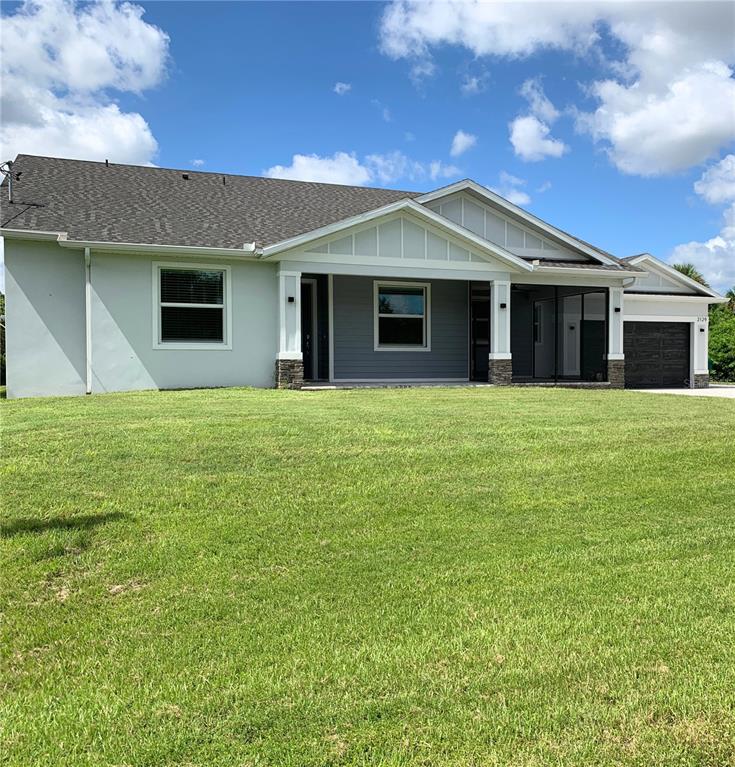 A single-story house with a light-colored exterior, stone accents, and a dark garage — 2120 LORRAINE DRIVE, PORT CHARLOTTE, FL