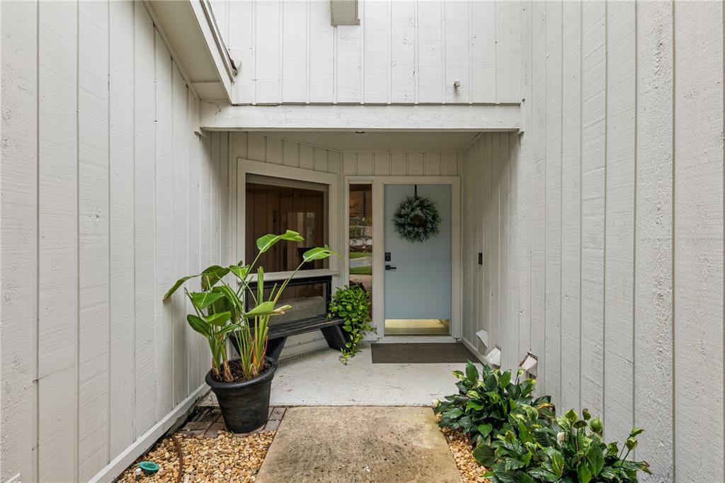 An exterior entryway features a light blue front door, a bench, and potted plants — 2538 LONG IRON COURT, LONGWOOD, FL