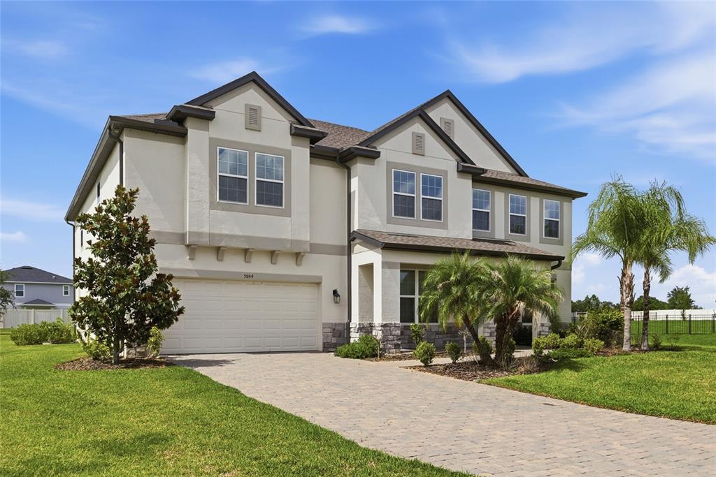 A two-story suburban house with a paved driveway, a two-car garage, and palm trees — 9844 CABERNET AVENUE, SEFFNER, FL