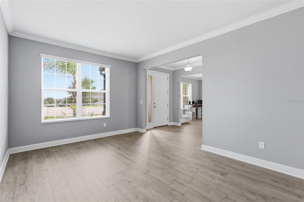 An empty room with light gray walls, wood-look flooring, and a view of an entryway — 9844 CABERNET AVENUE, SEFFNER, FL