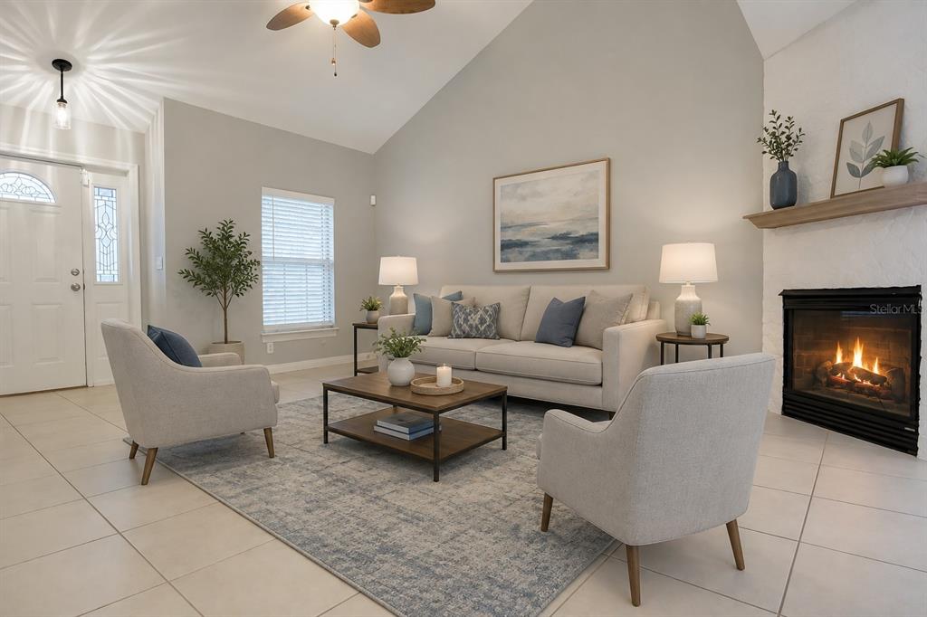 A living room features a vaulted ceiling, a fireplace, tile flooring, and neutral furniture — 183 HIGHLAND ROAD, TARPON SPRINGS, FL