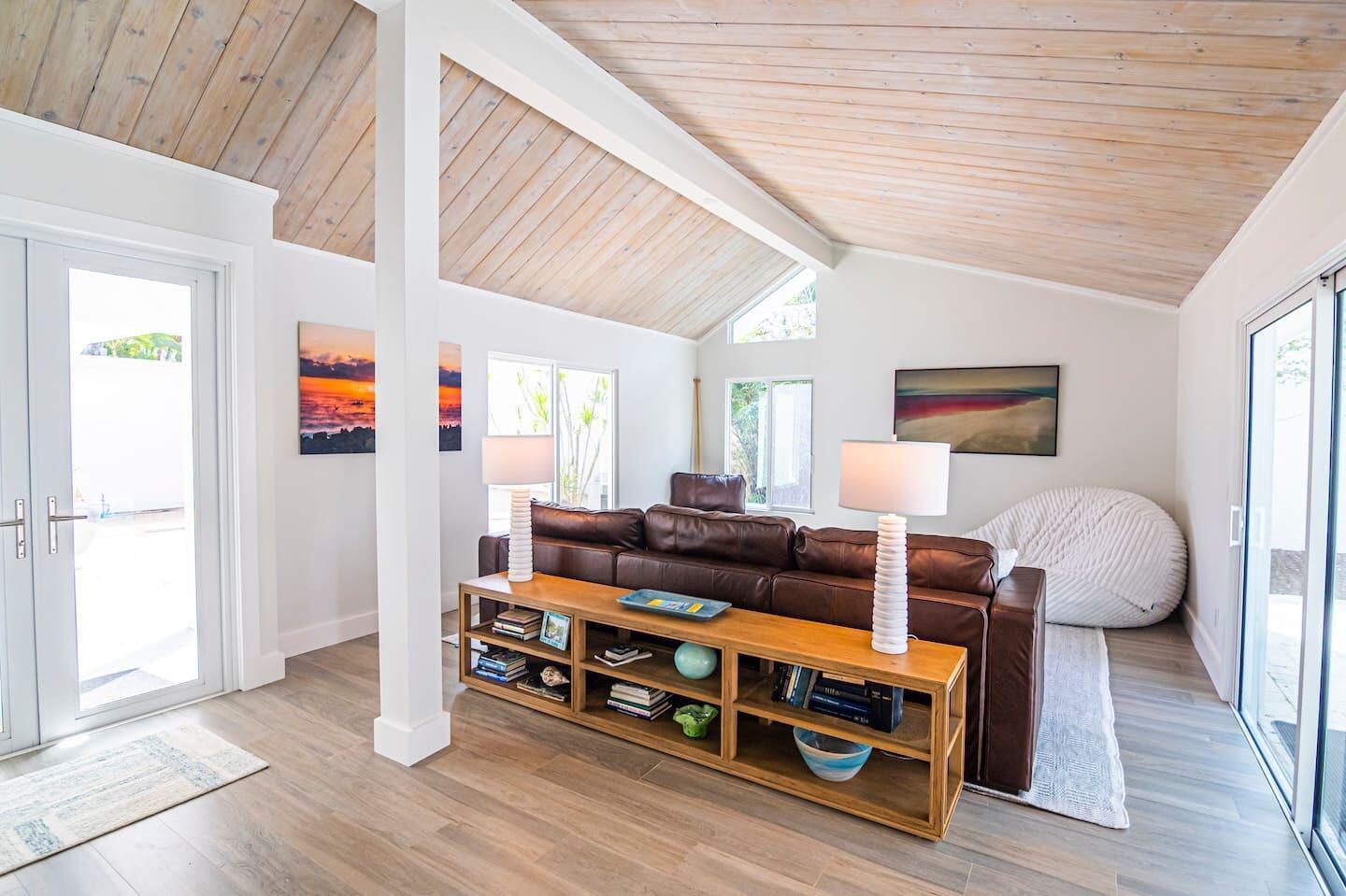 A living room features a brown leather sofa, wood console table, and vaulted wood-paneled ceiling — 103 W Sandpiper Circle W, Jupiter FL 33477, JUPITER, FL