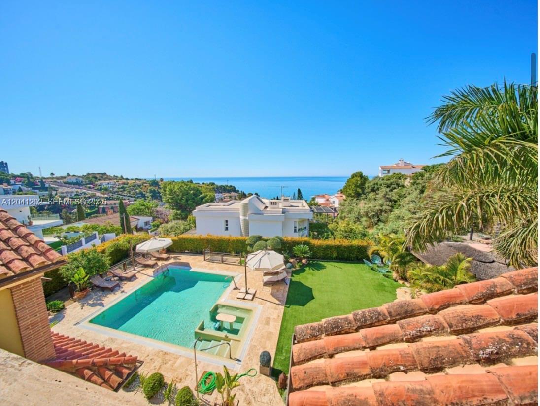 An elevated view of a swimming pool, lawn, and patio overlooking the distant ocean — 29018 MALAGA, ESPAIN, FL