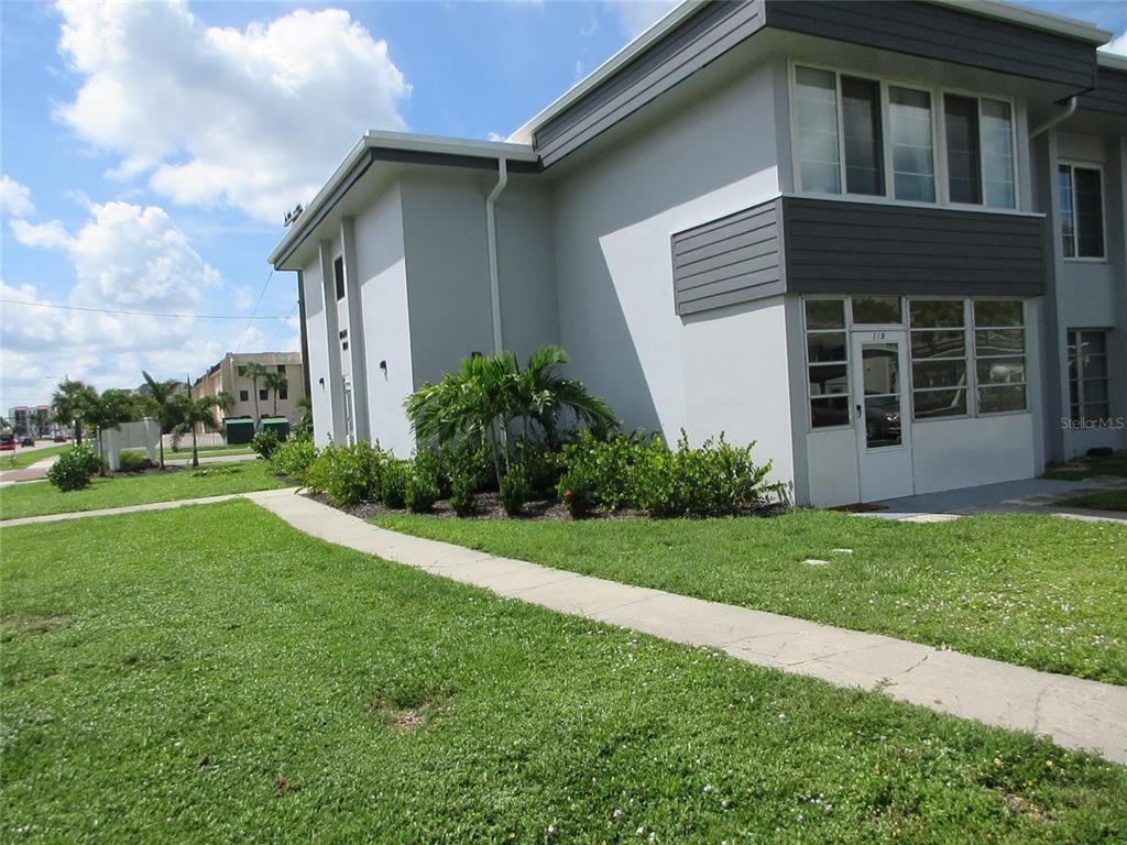 A two-story apartment building exterior with a concrete walkway and landscaped bushes — 21320 BRINSON AVENUE UNIT 119, PORT CHARLOTTE, FL
