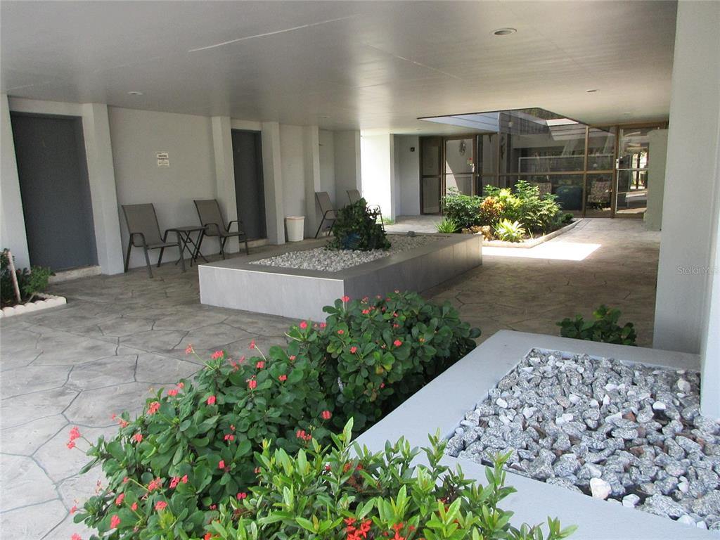 A covered outdoor patio features stone flooring, two raised gravel planters, and small flowering shrubs — 21320 BRINSON AVENUE UNIT 119, PORT CHARLOTTE, FL