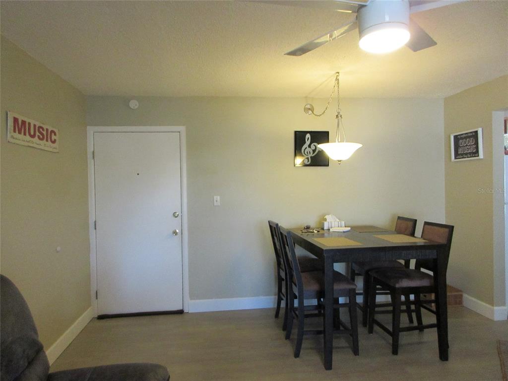 A dining area features a dark wood table with chairs under a hanging light fixture — 21320 BRINSON AVENUE UNIT 119, PORT CHARLOTTE, FL