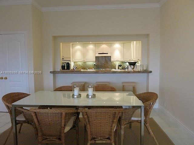 A dining area with a glass-topped table and wicker chairs sits before a kitchen pass-through — 201 Crandon Blvd # 1027, Key Biscayne FL 33149, KEY BISCAYNE, FL