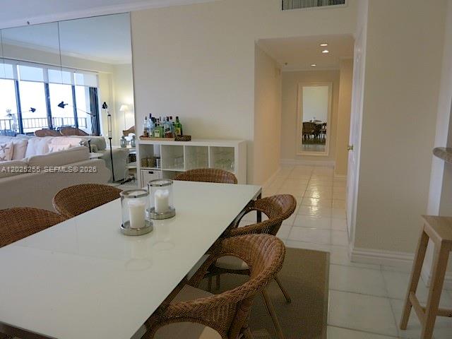 A dining area features a white table, wicker chairs, and a mirrored wall — 201 Crandon Blvd # 1027, Key Biscayne FL 33149, KEY BISCAYNE, FL
