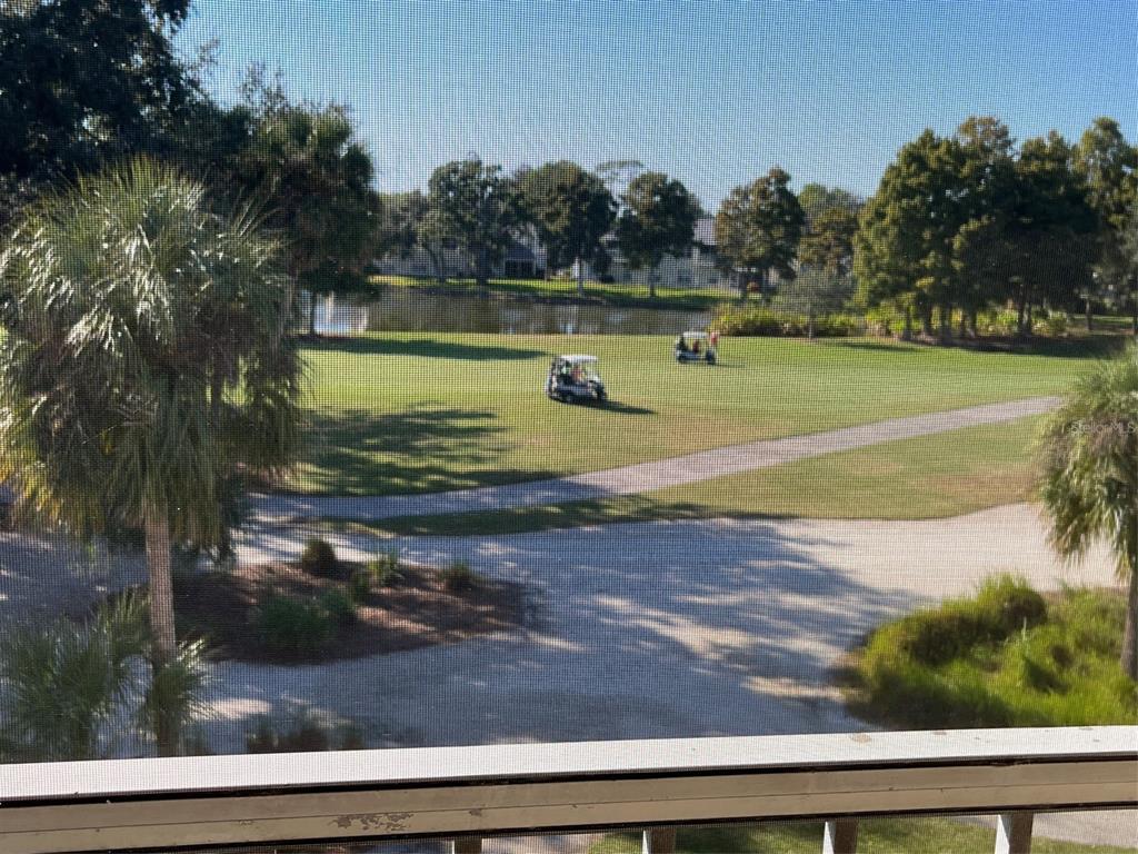 A view from a screened balcony overlooking a golf course, pond, and trees — 6501 STONE RIVER RD UNIT 306, BRADENTON, FL