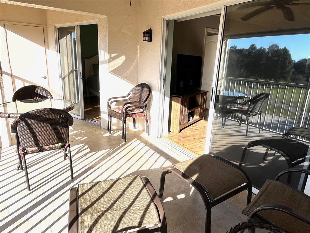 A covered balcony features wicker furniture, tiled flooring, and sliding glass doors leading indoors — 6501 STONE RIVER RD UNIT 306, BRADENTON, FL