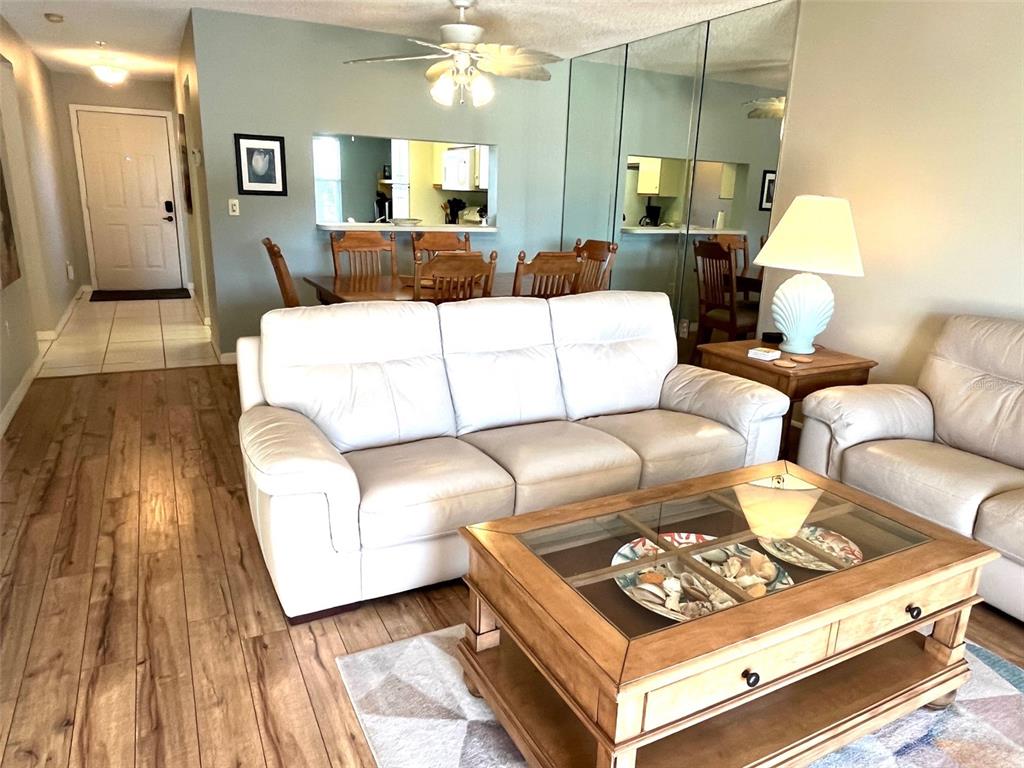 A living room features a white sofa, a wooden coffee table, and a dining area — 6501 STONE RIVER RD UNIT 306, BRADENTON, FL
